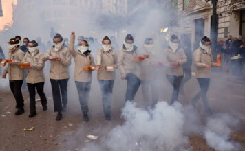 Grupo de personas en un desfile con niebla y cajas en las manos