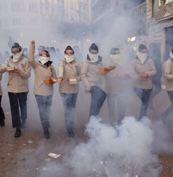 Grupo de personas en un desfile con niebla y cajas en las manos