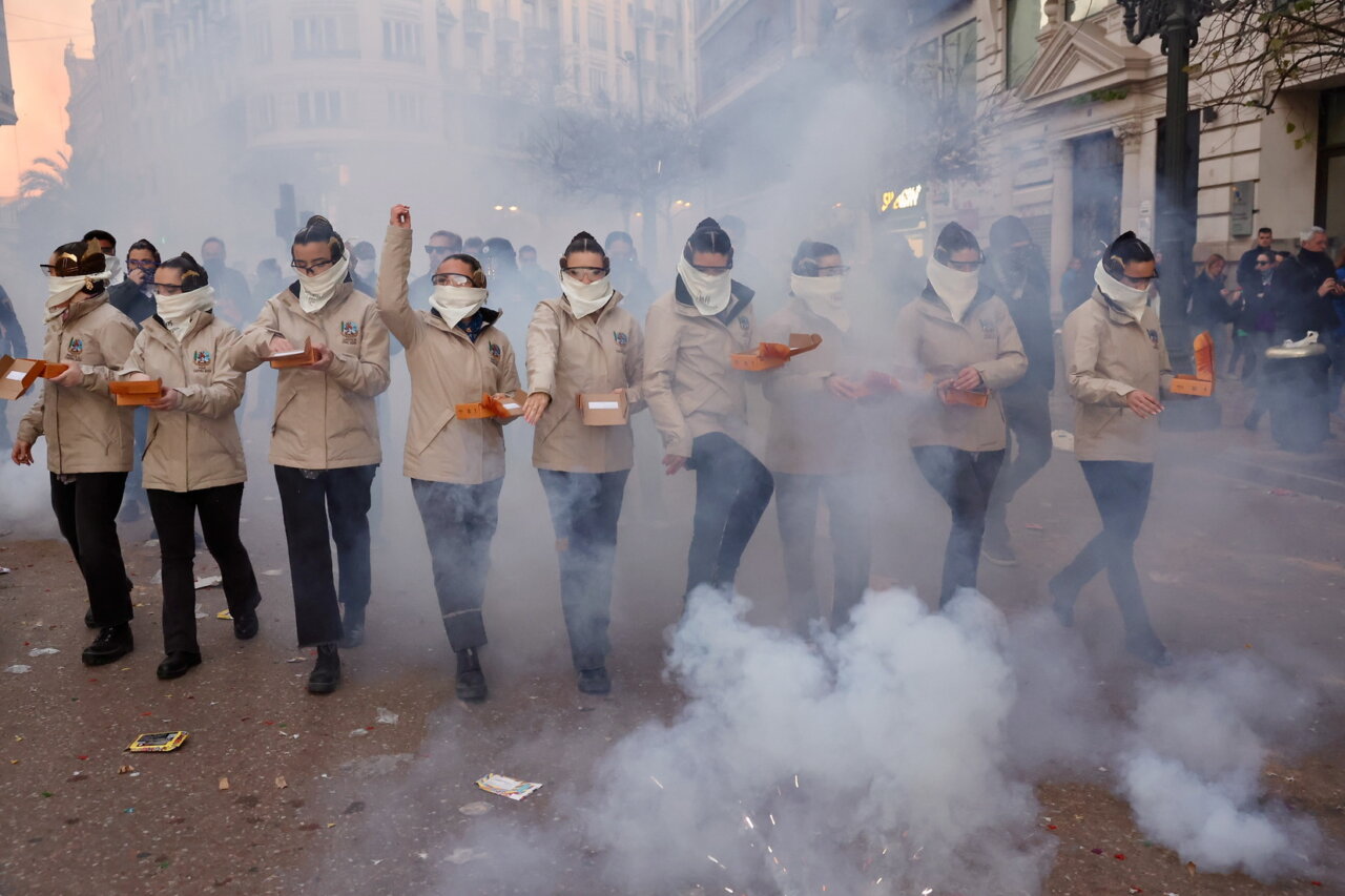 Grupo de personas en un desfile con niebla y cajas en las manos