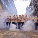 Grupo de personas en un desfile festivo con niebla en la calle