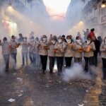 Grupo de personas en un desfile festivo con humo y confeti en la calle.