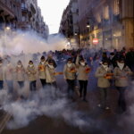 Grupo de personas en un desfile con humo y fuegos artificiales