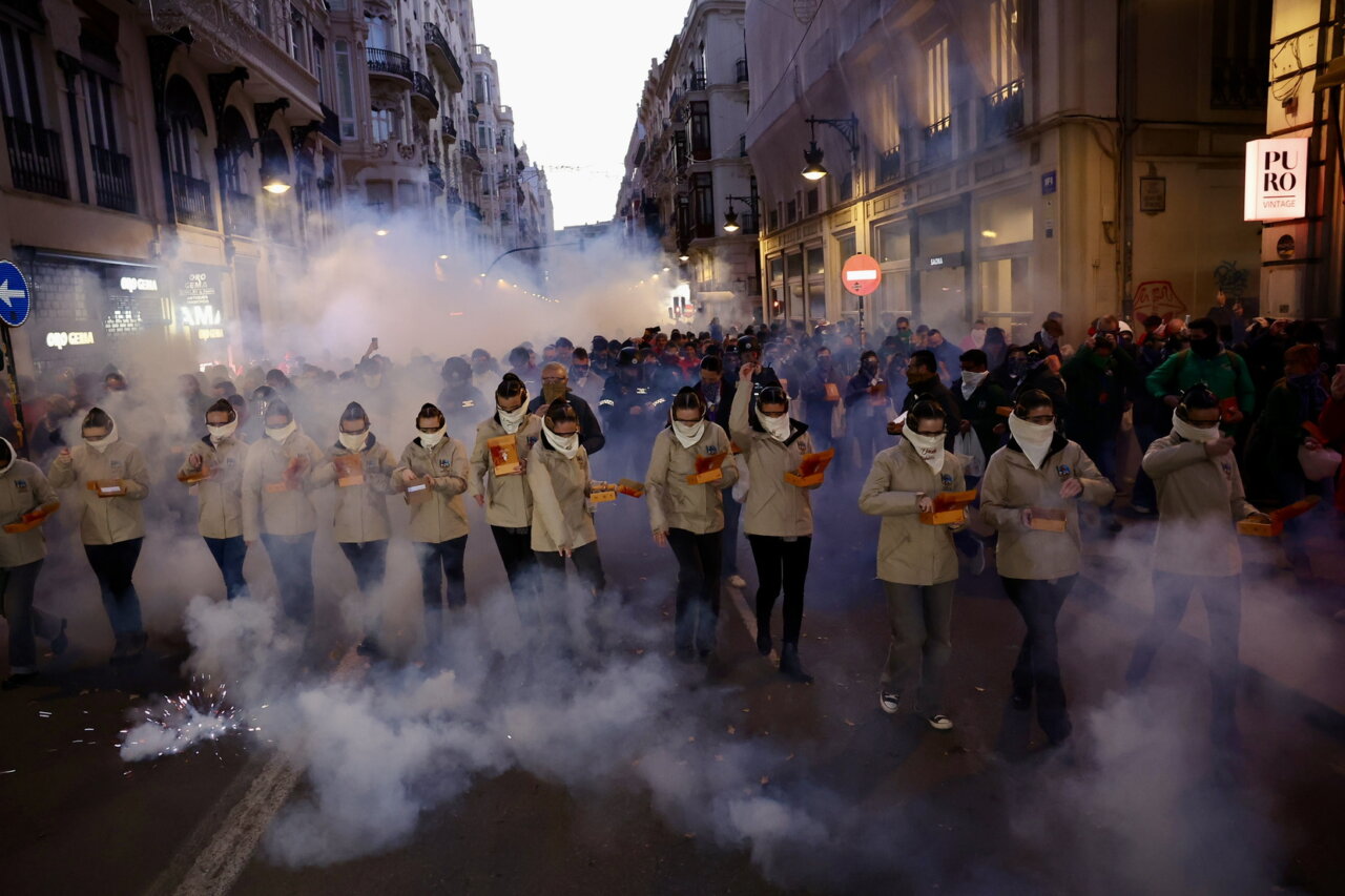 Grupo de personas en un desfile con humo y fuegos artificiales