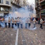 Grupo de personas en un desfile con humo y fuegos artificiales en Valencia