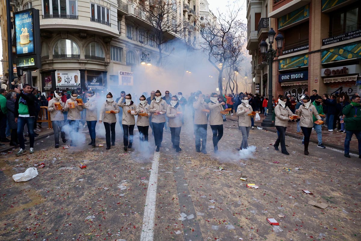 Grupo de personas en un desfile con humo y fuegos artificiales en Valencia