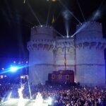 Celebración nocturna en Valencia con luces y multitudes frente a un castillo