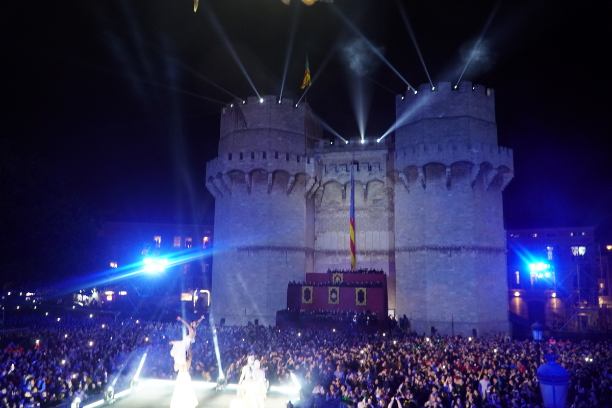 Celebración nocturna en Valencia con luces y multitudes frente a un castillo