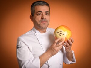 Chef sosteniendo el premio Sol Repsol 2026 en un fondo naranja