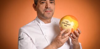 Chef sosteniendo el premio Sol Repsol 2026 en un fondo naranja