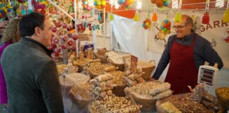 Hombre comprando frutos secos en un mercado festivo en Torrent.