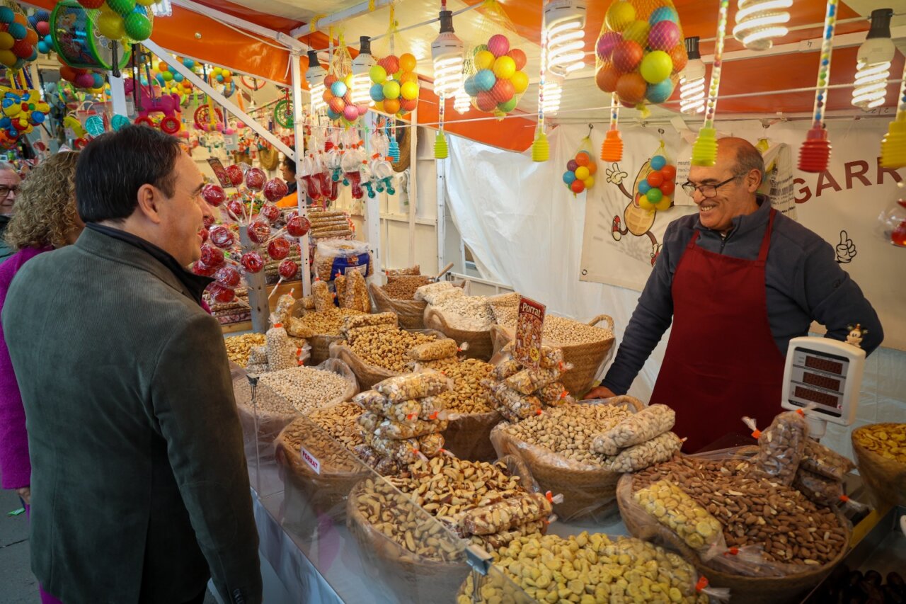 Hombre comprando frutos secos en un mercado festivo en Torrent.