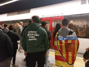 Grupo de personas en una estación de metro con bandera de Valencia CF