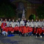 Grupo de personas posando en una plaza durante la noche