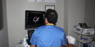 Médico realizando ecocardiografía a un paciente en consulta