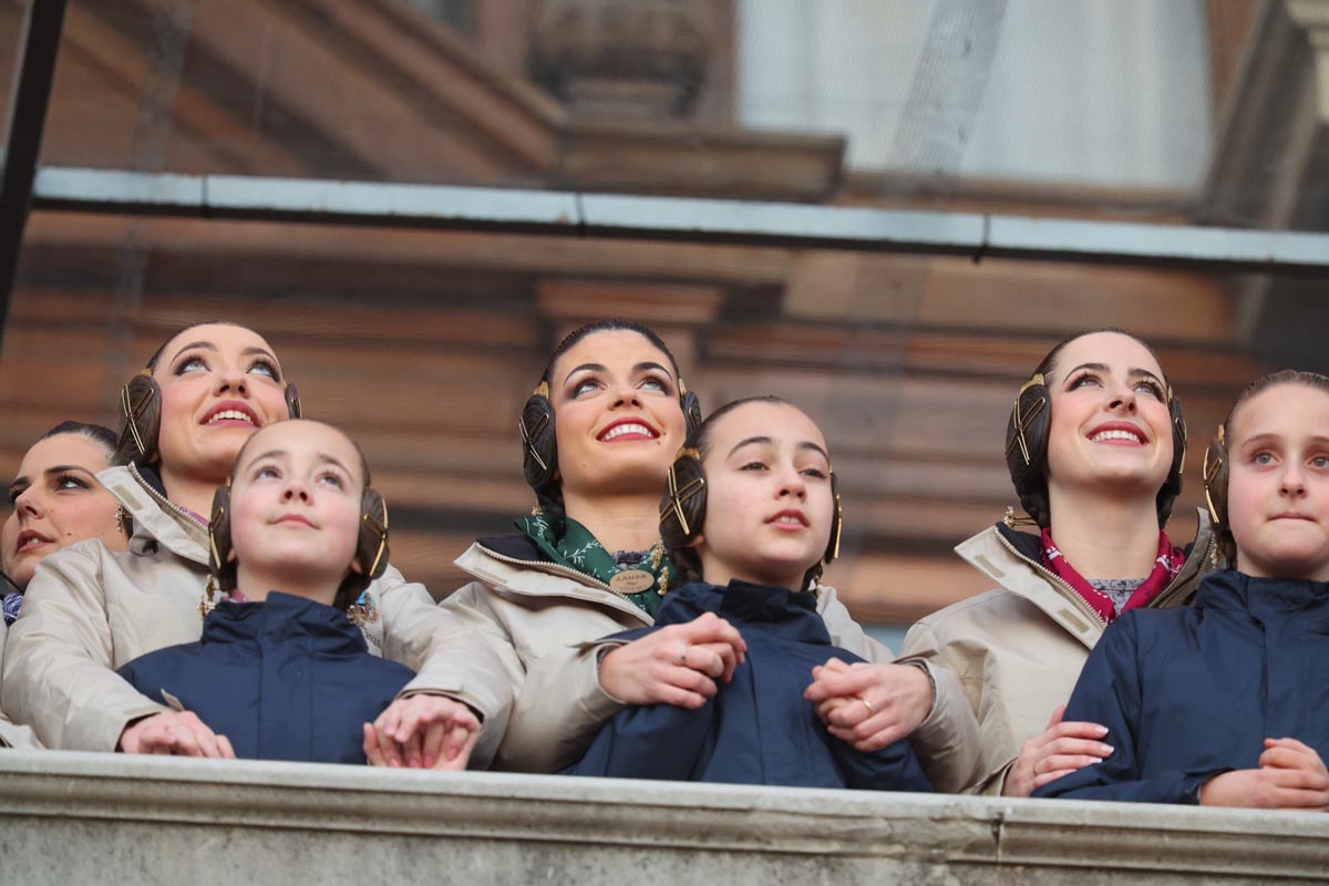 Mujeres y niñas con trajes tradicionales observando un evento