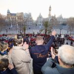 Multitud en celebración con personas saludando desde un balcón en Valencia
