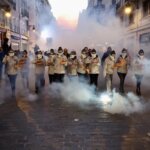 Grupo de personas en la calle con humo y cajas en las manos