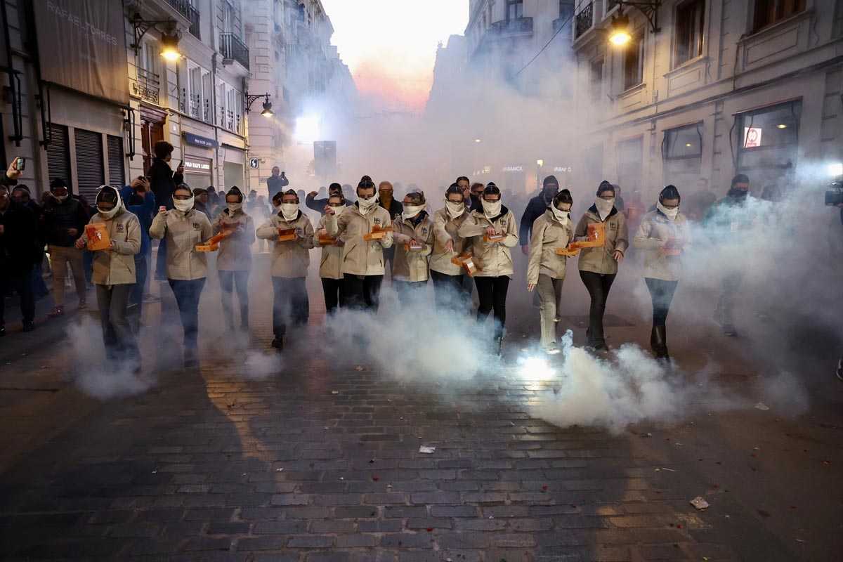 Grupo de personas en la calle con humo y cajas en las manos