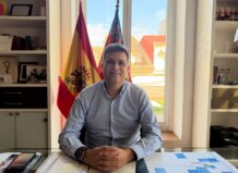 Juan Ramón Adsuara sentado en su oficina con banderas de España y Valencia