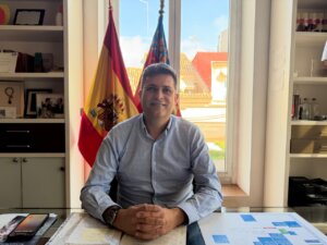 Juan Ramón Adsuara sentado en su oficina con banderas de España y Valencia