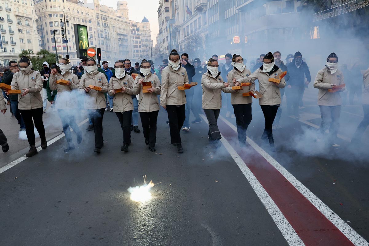 Grupo de personas en una manifestación con fuegos artificiales