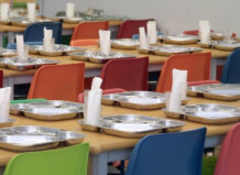 Mesas de un comedor escolar con platos y servilletas