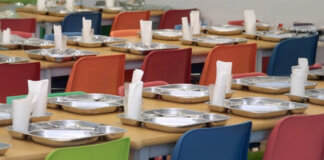 Mesas de un comedor escolar con platos y servilletas