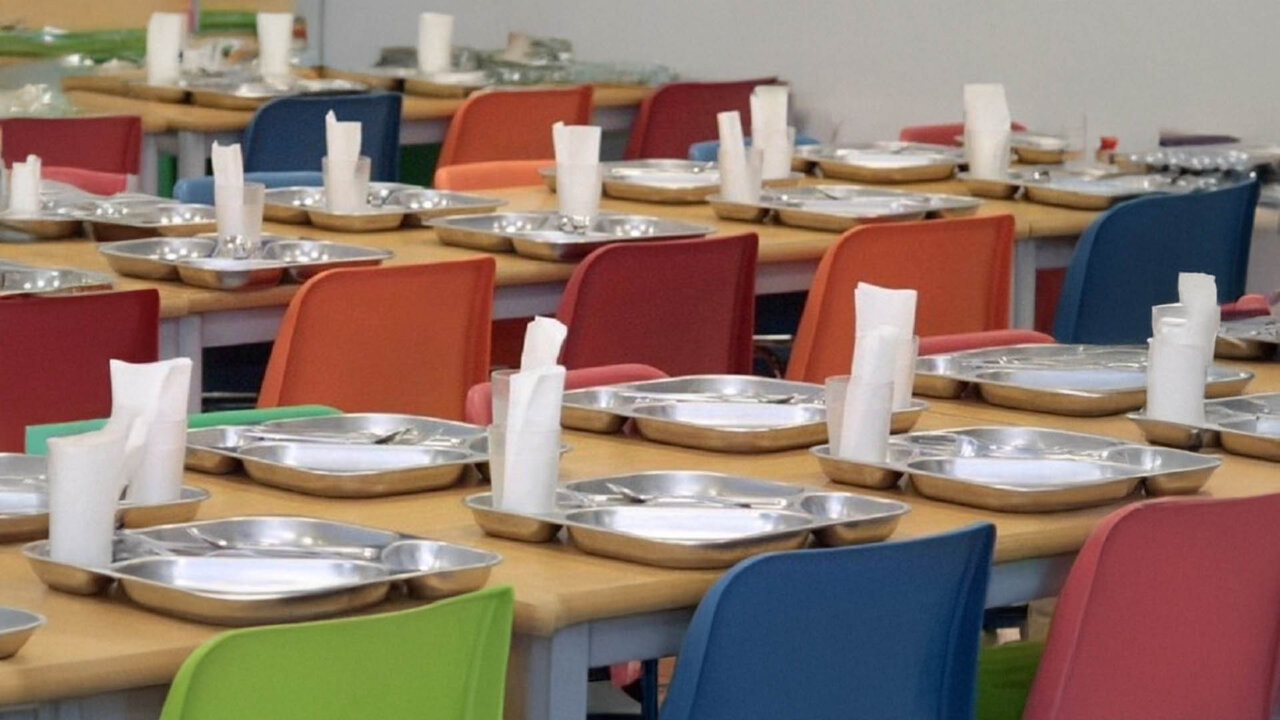Mesas de un comedor escolar con platos y servilletas