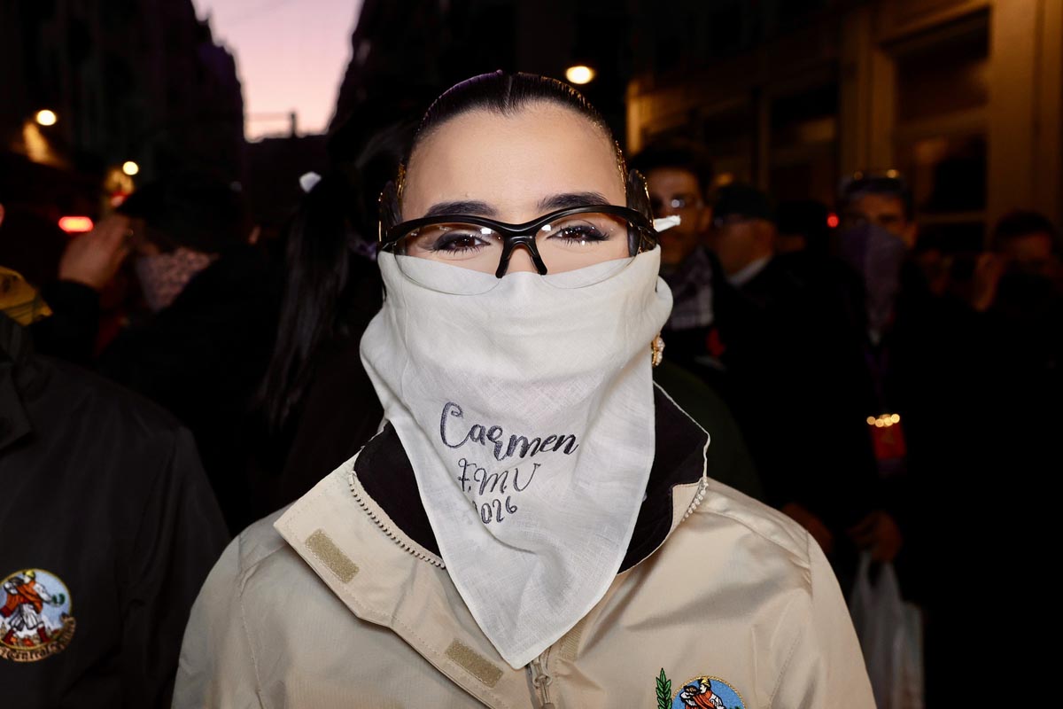 Mujer con bufanda blanca y gafas en un evento nocturno
