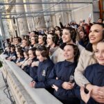 Grupo de mujeres sonriendo desde un balcón durante un evento