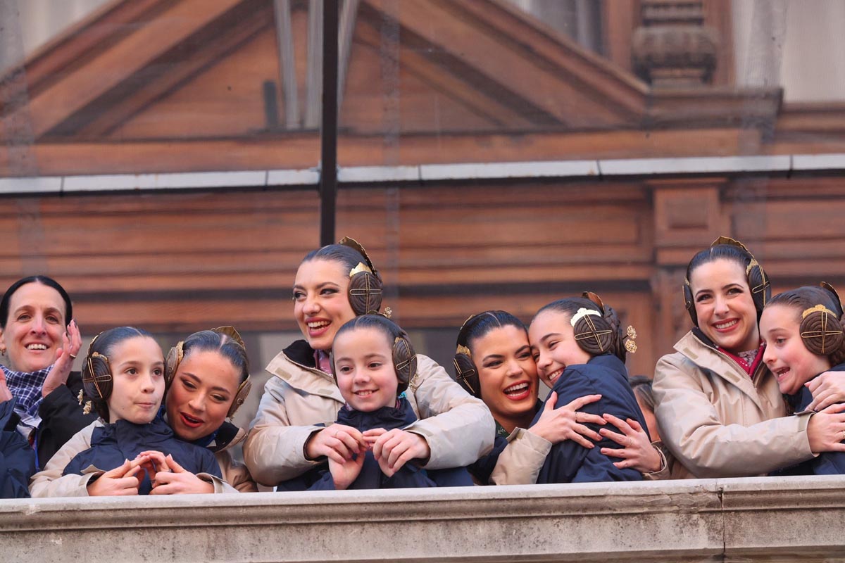 Grupo de mujeres y niñas con trajes tradicionales sonriendo y abrazándose