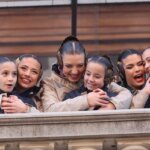 Grupo de niñas y mujeres sonriendo y abrazándose en un festival