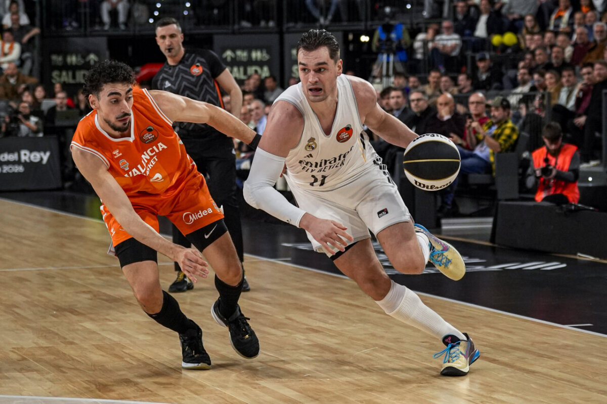 Jugadores de Valencia Basket y Real Madrid compiten por el balón en un partido emocionante.