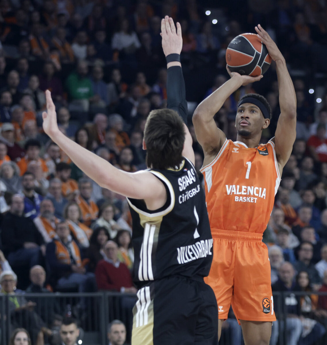 Jugador de Valencia Basket lanzando a canasta durante un partido emocionante.