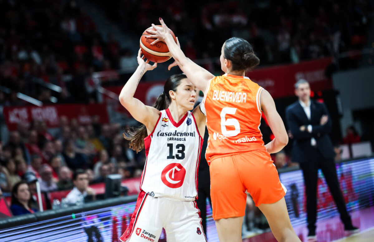 Jugadora de Casademont Zaragoza con balón frente a rival de Valencia Basket.