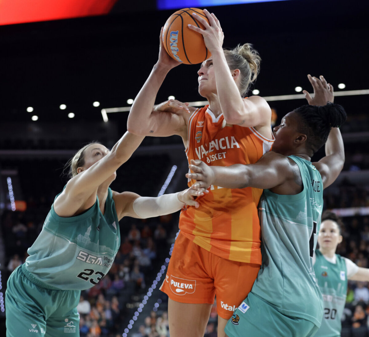Jugadora de Valencia Basket intenta anotar bajo la presión de dos rivales.
