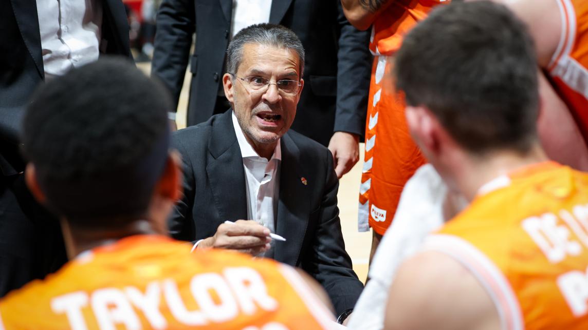 Entrenador de Valencia Basket dando instrucciones a sus jugadores durante un partido.