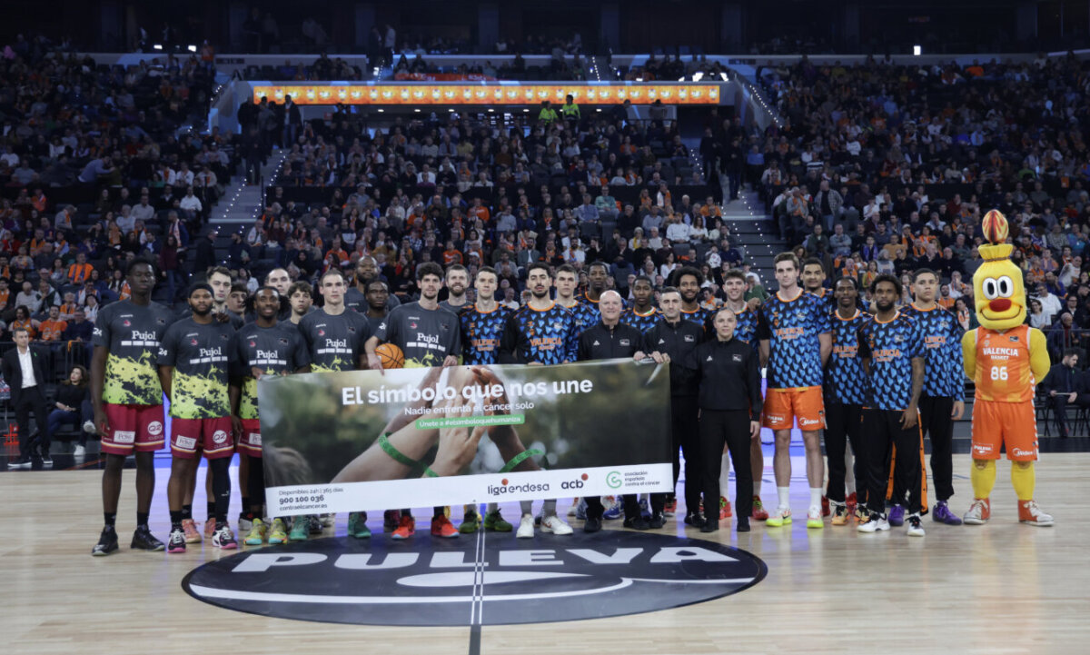 Jugadores de Valencia Basket y Lleida en el Roig Arena con un banner de apoyo al cáncer