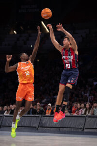 Jugadores de Valencia Basket y Baskonia compiten en un partido de baloncesto.