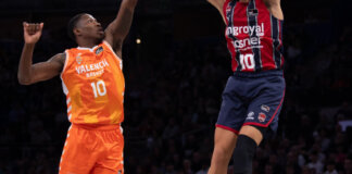 Jugadores de Valencia Basket y Baskonia compiten en un partido de baloncesto.