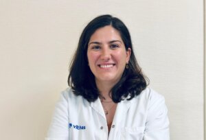 Doctora sonriente con bata blanca en un fondo claro