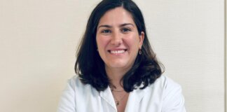 Doctora sonriente con bata blanca en un fondo claro