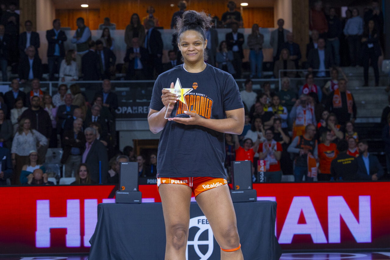 Jugadora del Valencia Basket femenino sosteniendo un trofeo de campeonas