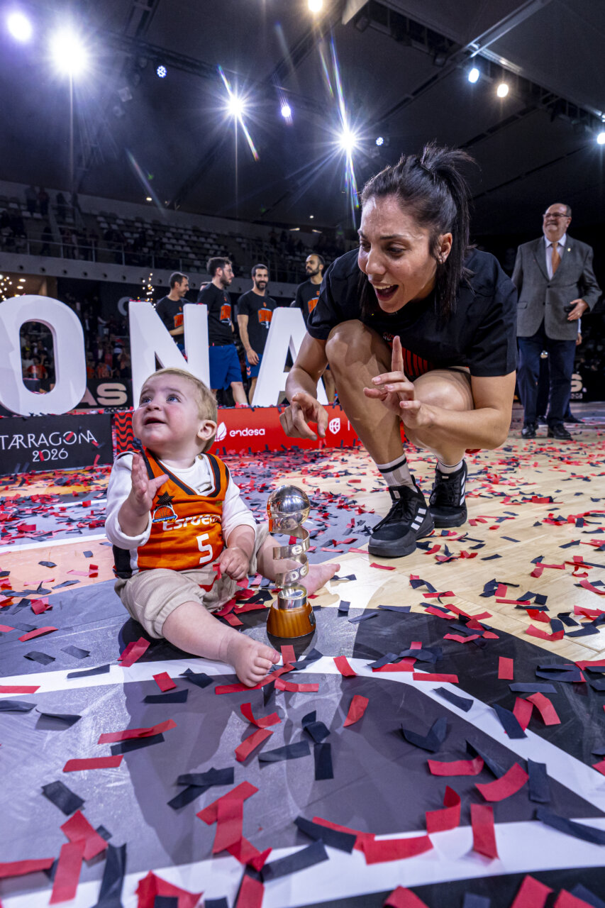Celebración del Valencia Basket femenino con un niño y un trofeo en la Copa de la Reina 2026.