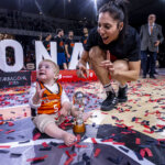 Niño con trofeo y jugadora de baloncesto celebrando en la cancha