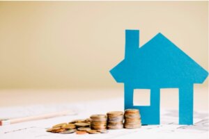 Modelo de casa de papel junto a monedas en una mesa