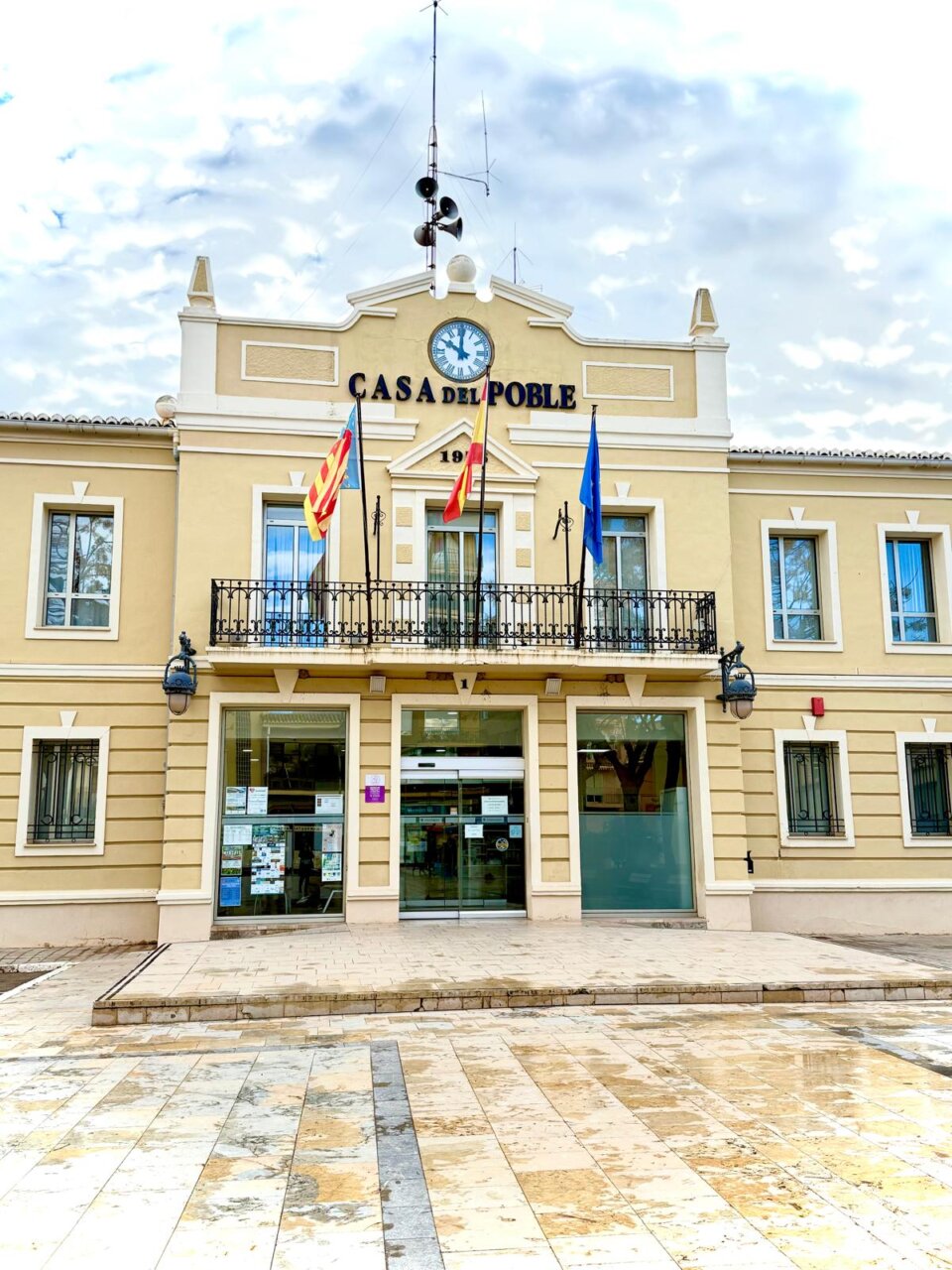 Fachada del Ayuntamiento de La Pobla de Farnals con banderas y reloj