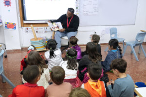 Un hombre lee un libro a un grupo de niños en un aula