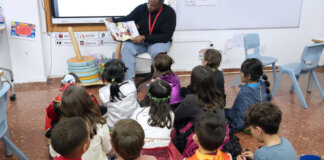 Un hombre lee un libro a un grupo de niños en un aula