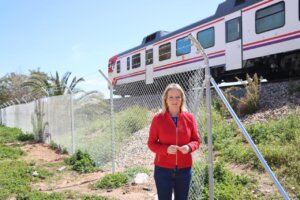 Mujer de pie junto a un vallado con tren en el fondo en Xirivella